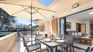Un patio al aire libre con mesa lista para comer, un sofá y una sombrilla grande.