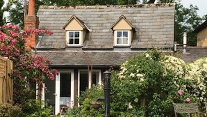 A two-story house with a sloped roof, a front door, and a small porch area. - Cornerstone Cottage -  a cotswold cottage that sleeps 2 guests  in 1 bedroom (Chipping Campden)
