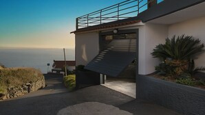 Ein modernes Haus mit einer Treppe, die zu einem Balkon mit Blick auf ein Gewässer führt.