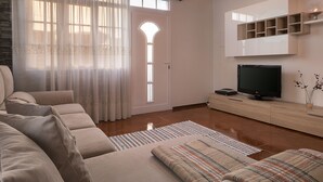 Ein modernes Wohnzimmer mit einer Sofagarnitur, einem Flachbildfernseher und einer Holzschrank.