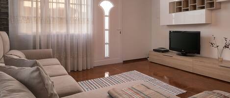A modern living room with a sofa set, a flat-screen TV, and a wooden cabinet.