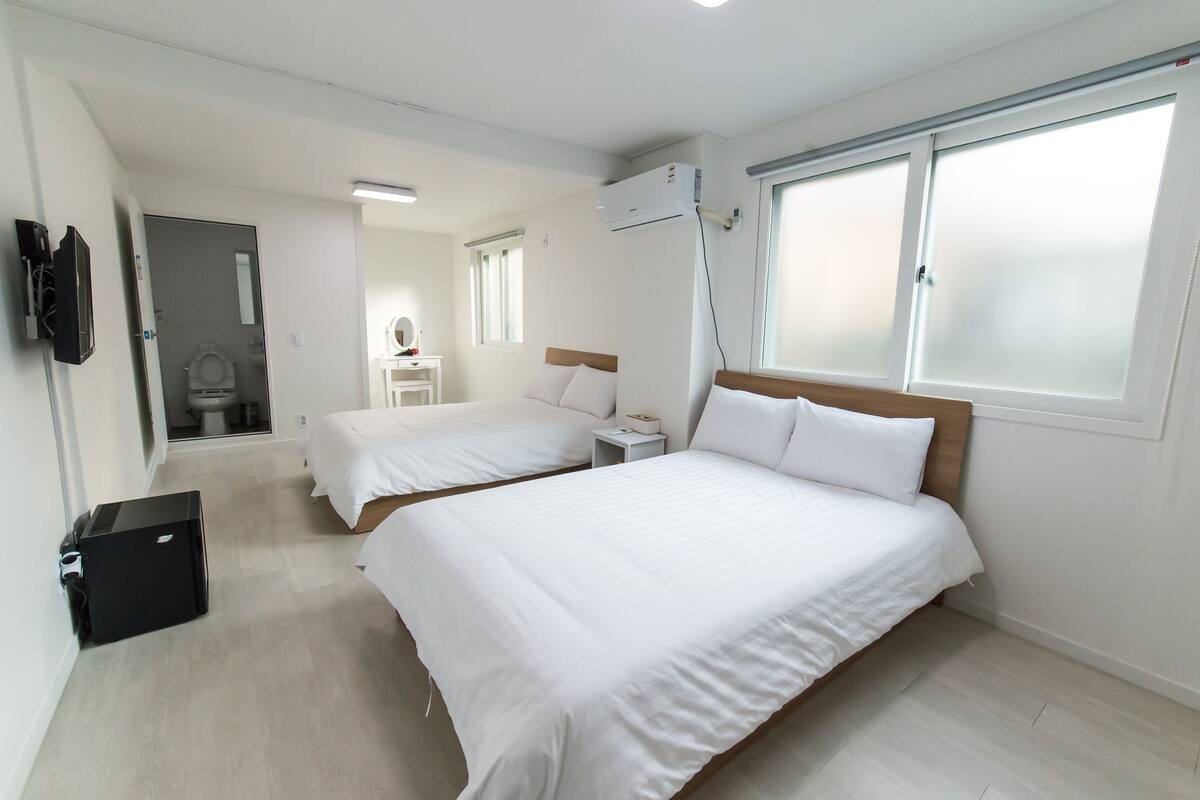 Une chambre d’hôtel avec deux lits, une petite table de chevet, un miroir et un appareil de climatisation.