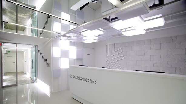 A modern, well-lit reception area with a clean, white design and a glass partition. - Kpop Haus (Seoul)