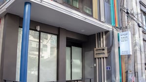 A modern building with a blue column, a sign reading "KPOP HAU", and a visible entrance. - Kpop Haus (Seoul)