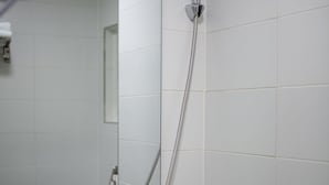 A bathroom with a white sink, a mirror, and a shower head. - Kpop Haus (Seoul)
