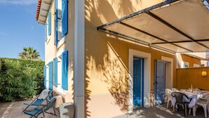 A covered outdoor seating area with a table and chairs, a door, and a small trash bin. - Wonderful  villa for 6 guests with pool, WIFI, TV and terrace (Fréjus)
