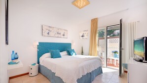 Un dormitorio con cama, televisión, mesita de noche y ventana con vistas al exterior.