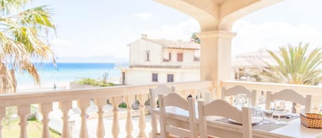 A balcony with white balustrades overlooking a beach and a building.