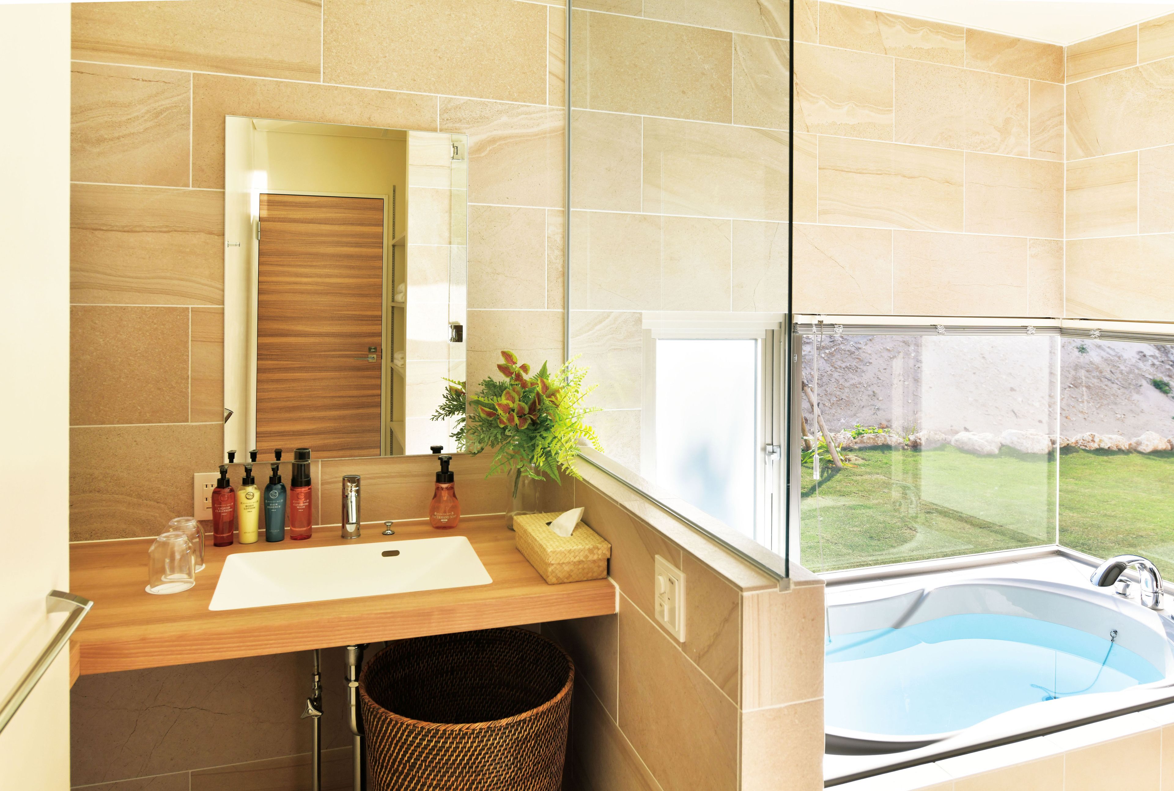 A bathroom with a wooden vanity, a large mirror, a sink, and a window overlooking a pool.