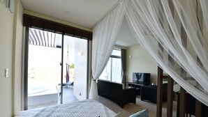 Een slaapkamer met een groot bed, een televisie en een balkon met een jacuzzi.