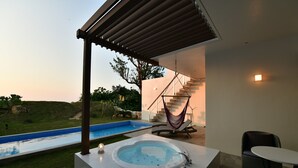 Een modern buitenzwembad met een jacuzzi, een hangmat en een trap naar een hoger gelegen terras.