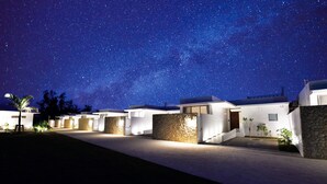 A row of modern, well-lit buildings with a clear night sky and visible stars.