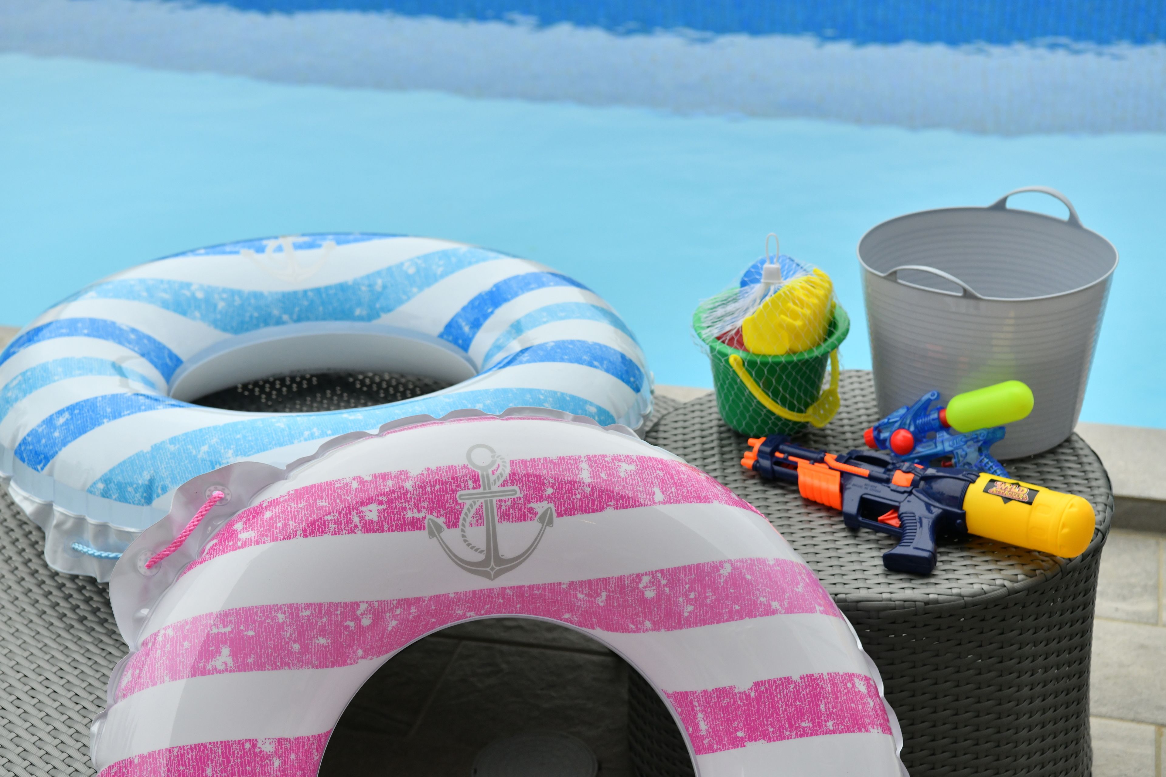 Een zwembadgedeelte met een ligstoel, een strandbal, een speelgoedpistool en een prullenbak.