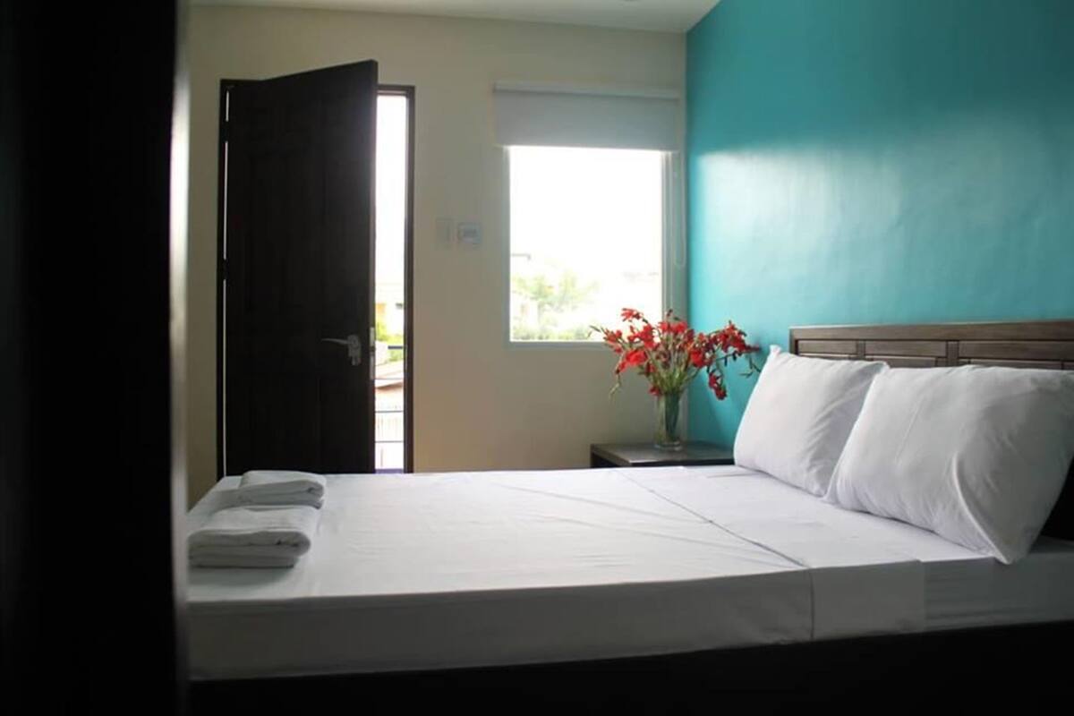 A hotel room with a bed, a window, and a door.