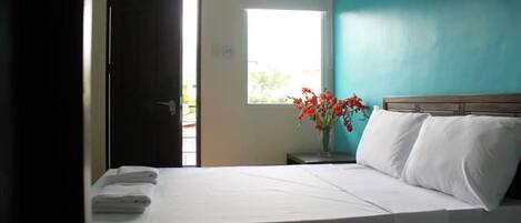 A hotel room with a bed, a window, and a door.