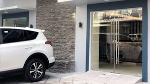 A modern building with a white SUV parked in front. - Rana Hotel (Cebu City)