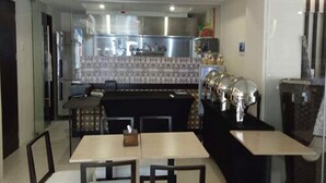 A modern kitchen with a central island, dining area with chairs, and a refrigerator. - Rana Hotel (Cebu City)