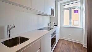 A modern kitchen with white cabinetry, stainless steel appliances, and a window providing natural light.