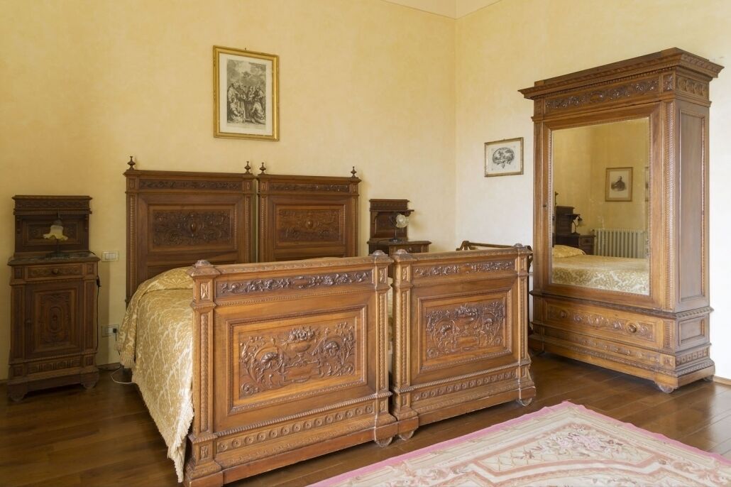 Een slaapkamer met een groot houten bed, een dressoir, een spiegel en een lijst met een foto aan de muur.