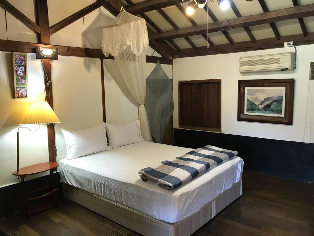 A bedroom with a bed, bedside table, lamp, and a window with a view.