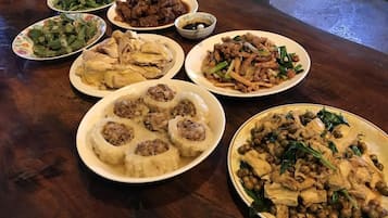 A wooden table with various dishes including meatballs, stir-fried vegetables, and a dish with chicken and peanuts.