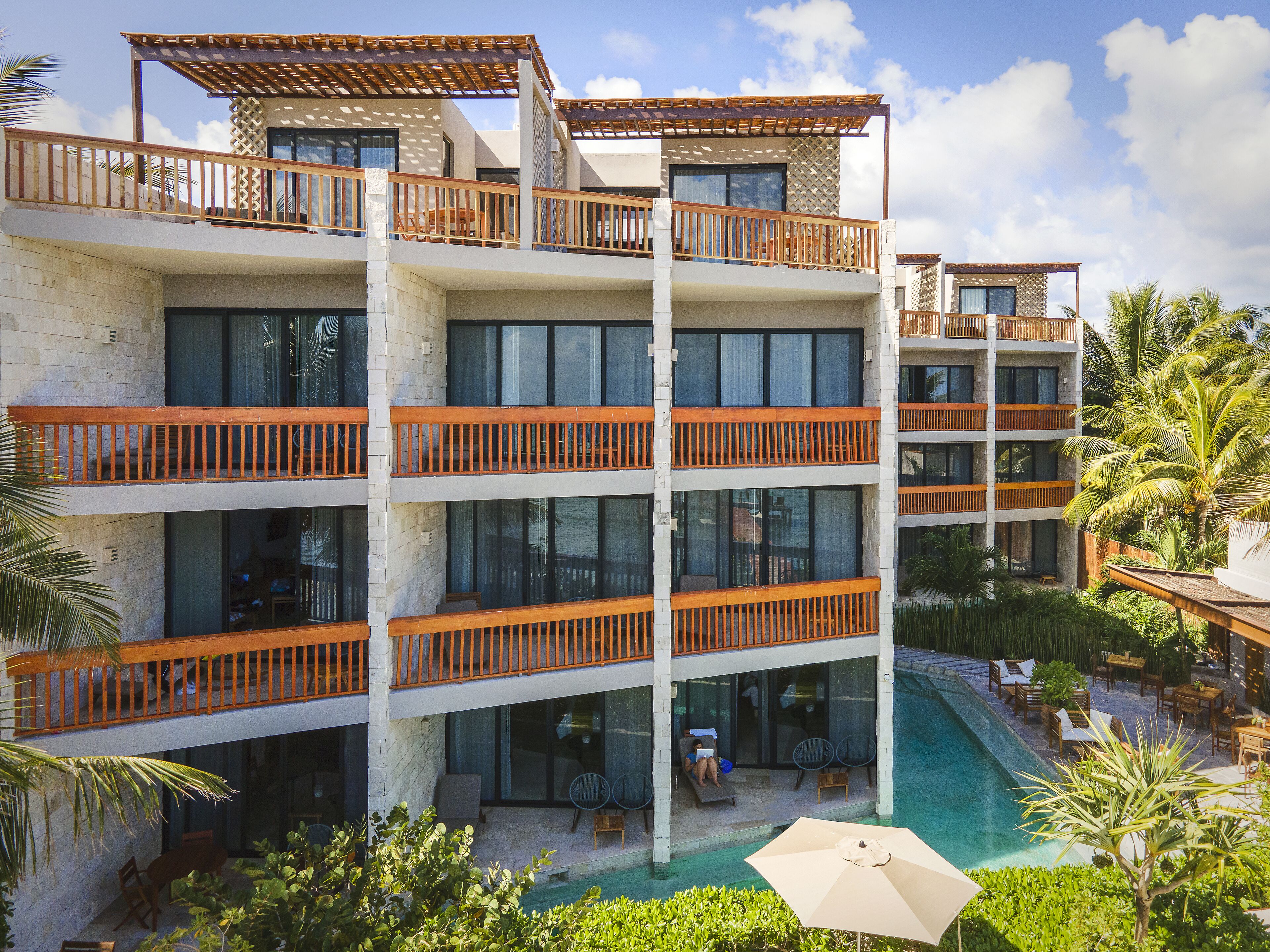 A multi-story hotel with balconies, a swimming pool, and outdoor seating.