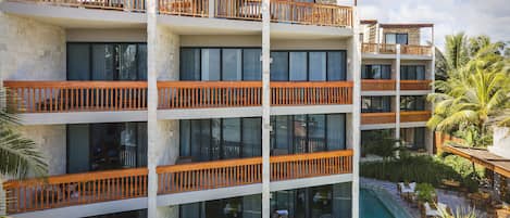 A multi-story hotel with balconies, a swimming pool, and outdoor seating.