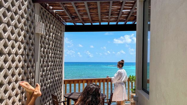 Un espace piscine avec vue sur l’océan, une terrasse en bois et un coin salon abrité.