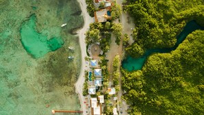 Vue aérienne d’une station balnéaire comprenant plusieurs hébergements de type bungalow, une piscine et une plage.