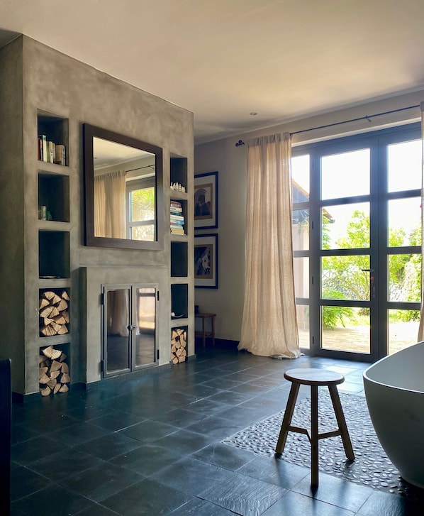 Une salle de bain spacieuse avec une grande baignoire, un miroir et une cheminée.