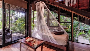 A room with a bed under a canopy, large windows, and a view of greenery outside. - Vida Silvestre Tulum (Tulum)