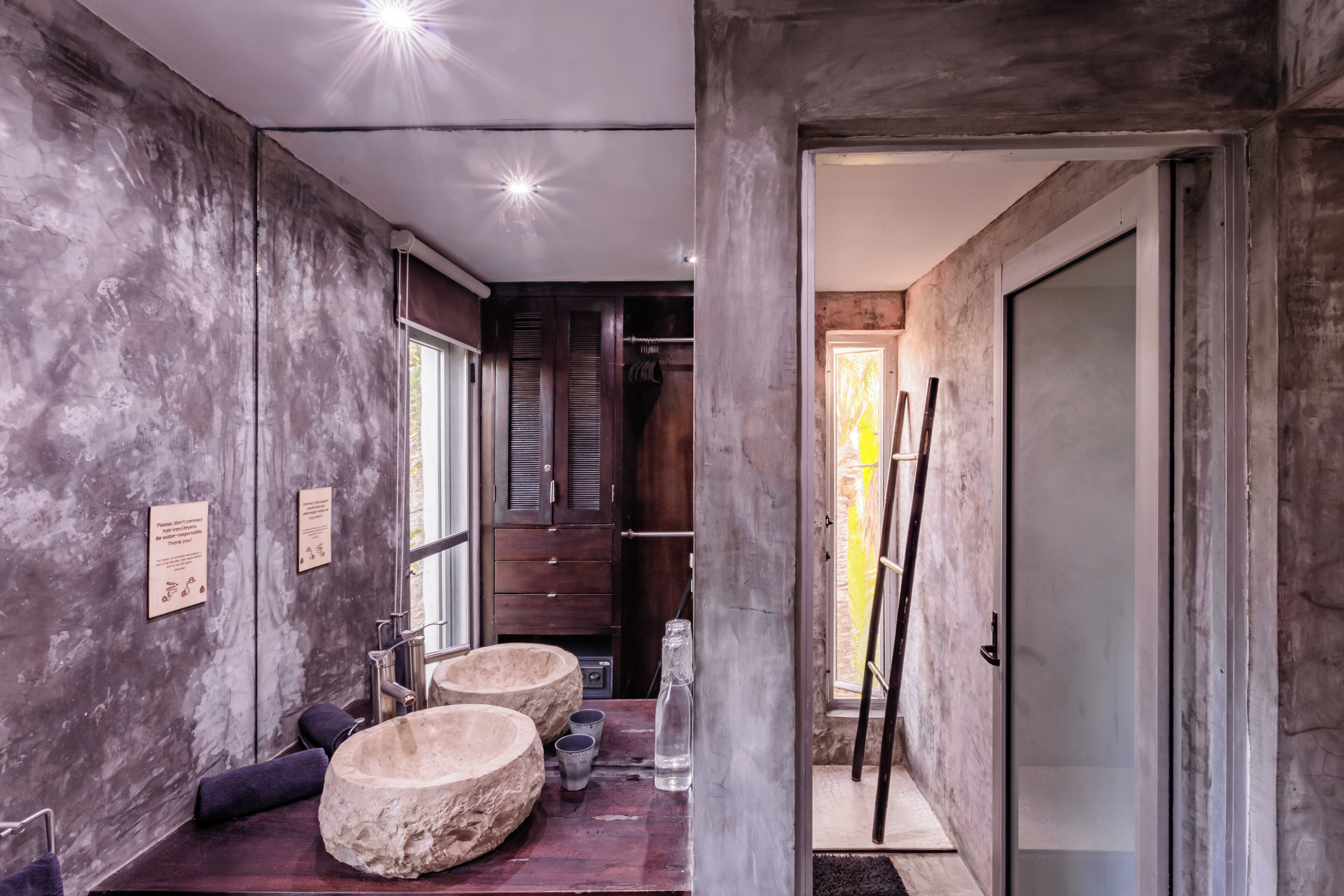 A modern bathroom with a large mirror, two stone basins, and a wooden vanity.