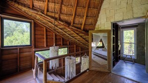 A wooden cabin with a thatched roof, wooden walls, and a balcony with macrame decorations. - Vida Silvestre Tulum (Tulum)