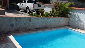 En swimmingpool med en mur av sten och en vit pickup-truck parkerad i närheten.