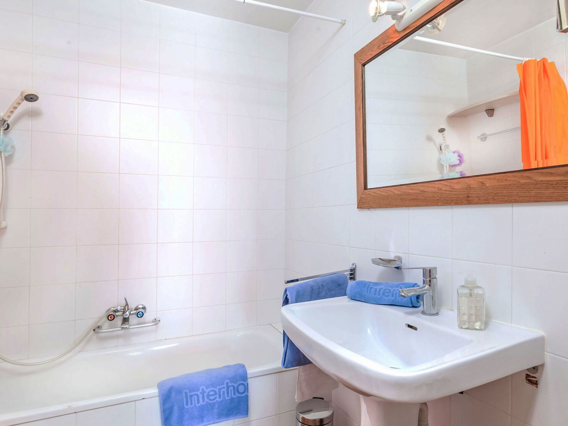 Un baño con bañera, lavamanos, espejo y ducha.