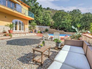 Un espace patio avec une piscine, du mobilier d’extérieur et un mur en pierre.