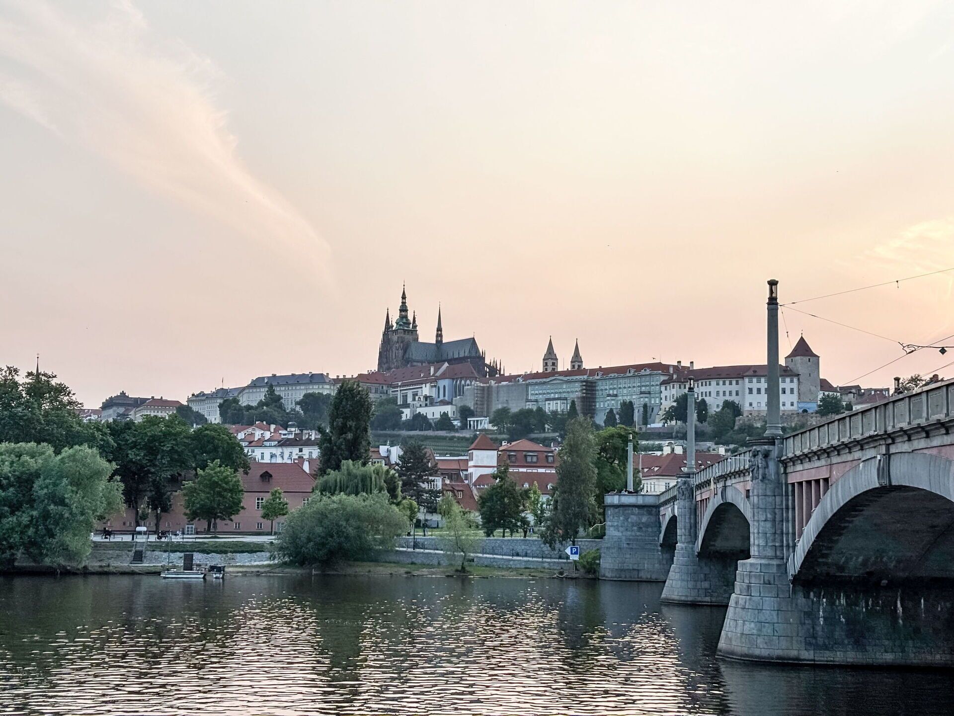 Un ponte storico che sovrasta un fiume, con uno skyline urbano sullo sfondo, tra cui una cattedrale imponente.