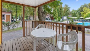 A covered outdoor area with a wooden deck, a round table, and two chairs. - Beautiful private villa for 4 people with WIFI, pool, terrace and pets allowed (Prague)