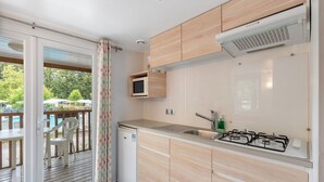 A compact kitchen with wooden cabinets, a built-in microwave, a gas stove, and a sink. - Beautiful private villa for 4 people with WIFI, pool, terrace and pets allowed (Prague)