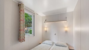 A single bed with a patterned bedspread, a window with curtains, and wall-mounted lights. - Beautiful private villa for 4 people with WIFI, pool, terrace and pets allowed (Prague)