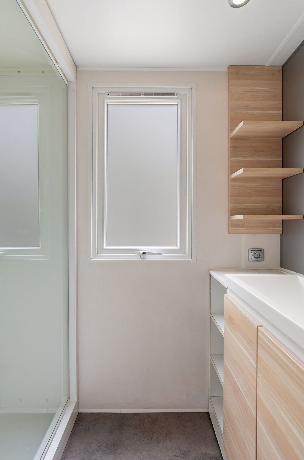 Un baño con ventana, lavamanos y espejo.