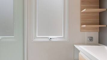 Un baño con ventana, lavamanos y espejo.