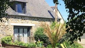 A stone house with a sloped roof, a front porch, and a well-maintained lawn. - A 2 bedroom gite sleeping 4 plus a cot with access to a heated covered pool. (Henansal)