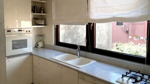 A kitchen with a gas stove, a built-in oven, a sink, and a window with a view of the outside.