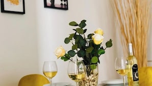 A dining table with white plates, wine glasses, and a vase with yellow roses.