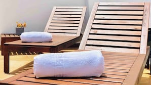Two wooden lounge chairs with white towels, a small table, and a potted plant.