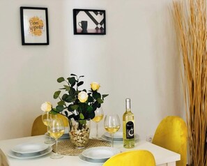 Una mesa de comedor preparada con platos, copas, una botella de vino y un florero con flores.