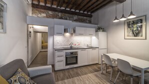 A modern kitchen with white cabinets, a built-in oven, and a stainless steel sink. There is a dining table with chairs and a pendant light above. - GUELFA HOUSE: restructuring, on the ground floor, comfortably accommodates 6 people  (Firenze)