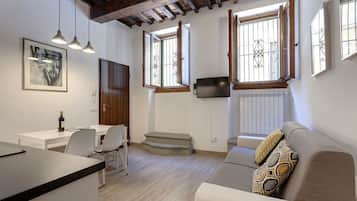 Un salon moderne comprenant un canapé, un coin repas avec une table et des chaises, et un espace cuisine avec un comptoir.