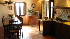 Una cocina tradicional con comedor, armarios de madera, piso de baldosas y una araña.